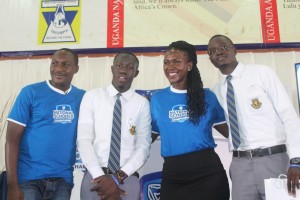 Adengo, Head of CSI and Communications Stanbic Bank (2nd right) and Brain Mulondo the quiz master of the Stanbic National Schools Championship pose for a group photo with students from Teso College Aloet